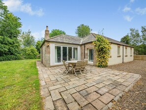 A stone house with a patio, a dining table, and chairs.