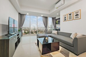 A modern living room with a large window, a sofa, a coffee table, and a TV on a stand. - Alvo by Kozystay - Kemang (Jakarta)
