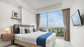 Een moderne hotelkamer met een groot bed, een nachtkastje, een televisie en uitzicht over de stad.
