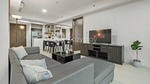 Een moderne woonkamer met een grijze bank, een salontafel en een flatscreen televisie waarop 'NETFLIX' wordt weergegeven.