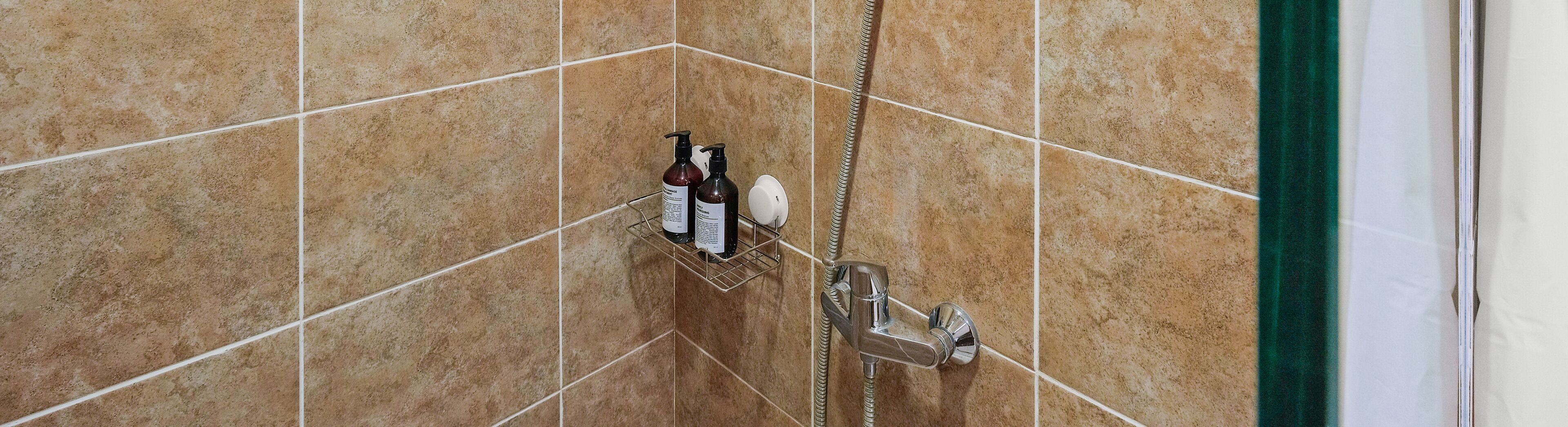 Kylpyhuoneessa on suihku, käsienkuivaaja ja hygieniatarvikkeet hyllyllä.