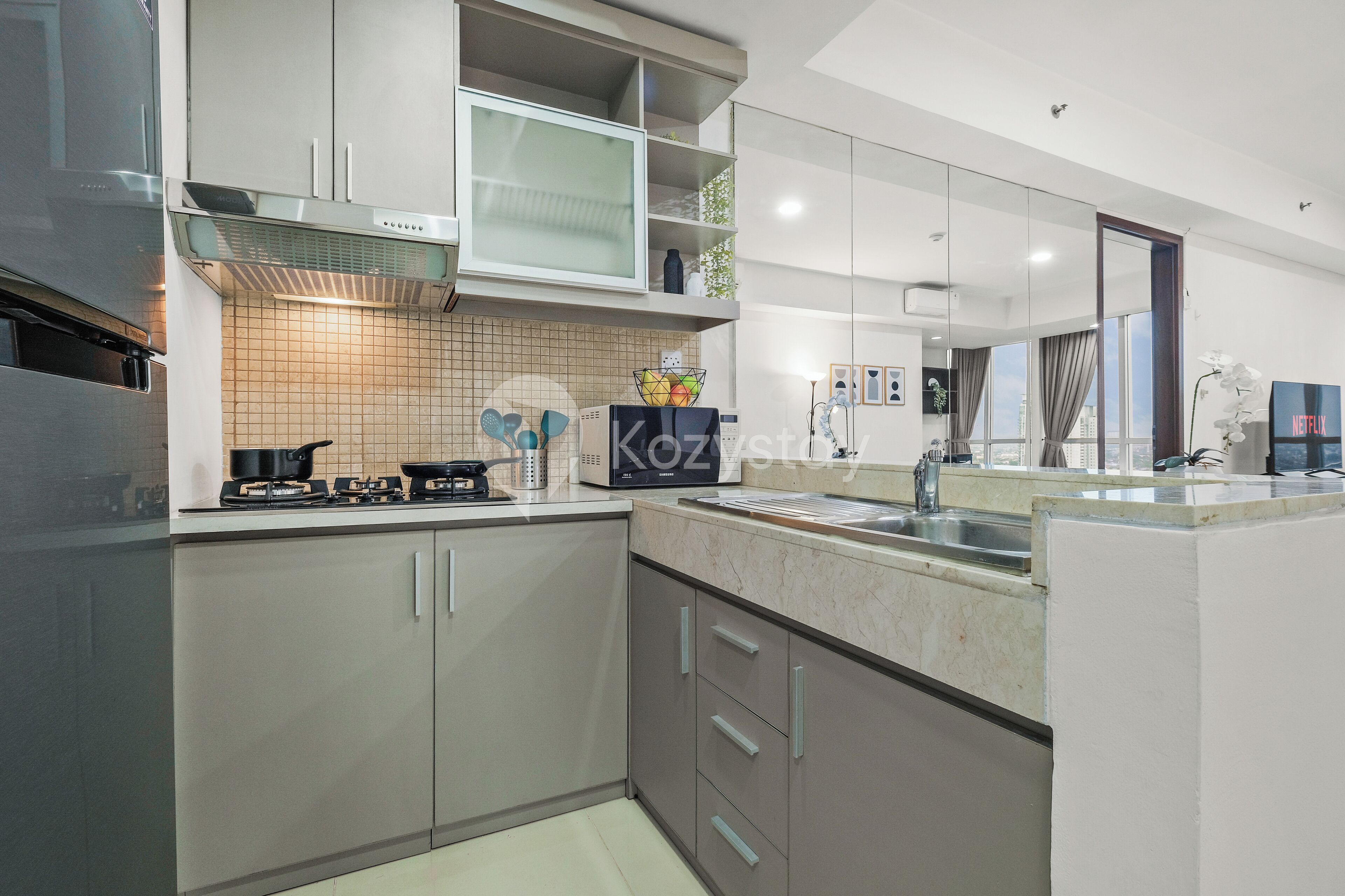 A modern kitchen with stainless steel appliances, a microwave, and a kettle on the countertop.