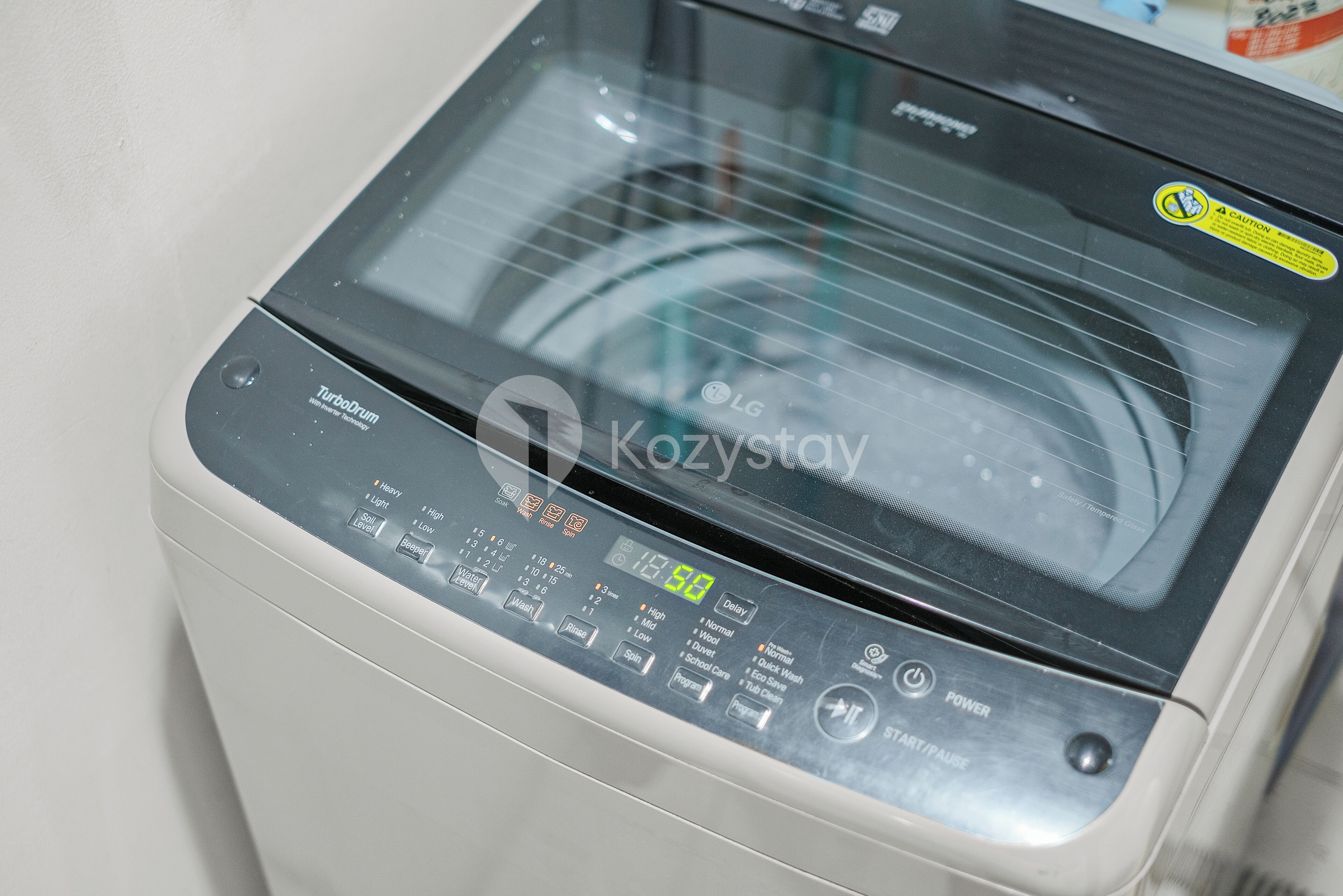 A front view of a washing machine with control panel, brand name, and model number visible.
