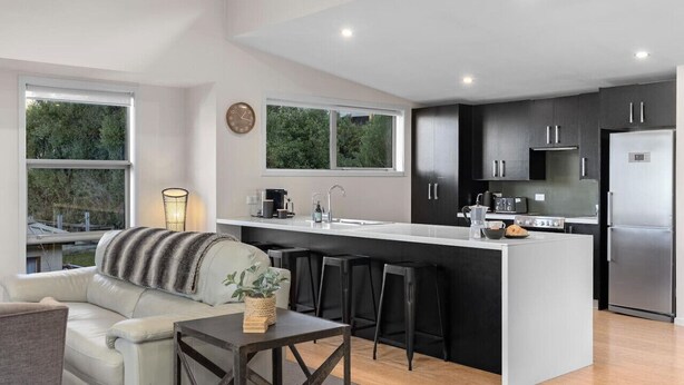 A modern kitchen with a central island, bar stools, and a dining table. - Mountain Views on Sainsbury (Queenstown)