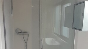 A glass-enclosed shower area with a handheld showerhead, a white sink, and a mirror on the wall. - 4 Guests - Pet Friendly - 13 min to the Beach (Bournemouth)