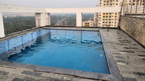 A rooftop swimming pool with a view of surrounding buildings. - Xanadu Studio Apartment # 902 (Kolkata)