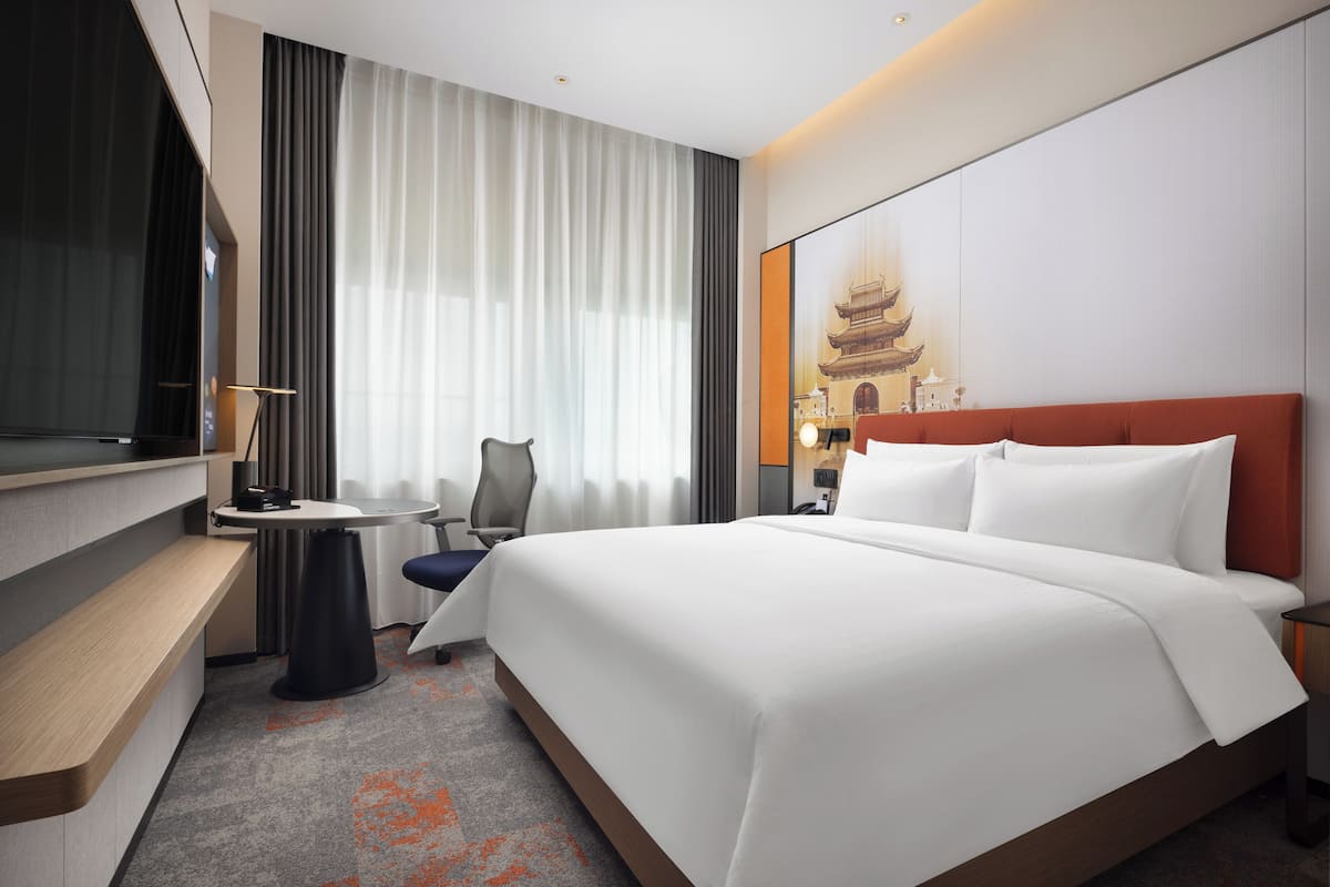 Une chambre d’hôtel moderne, dotée d’un grand lit, d’un bureau et d’une chaise.