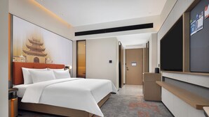 Ein modernes Hotelzimmer mit einem großen Bett, einem Flachbildfernseher und einem großen Fenster.