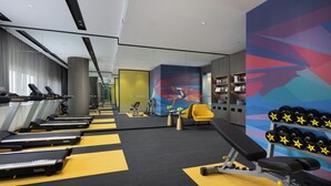 Ein Fitnessraum mit Laufbändern, einer Hantelbank und Kurzhanteln.