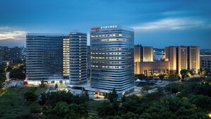 Ein modernes Hotel mit gewölbter Fassade, mehreren Etagen und auffälliger Beschilderung.