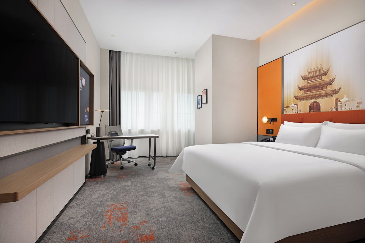 Une chambre d’hôtel équipée d’un lit, d’un bureau, d’une chaise et d’un téléviseur.