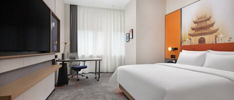 A hotel room with a bed, desk, chair, and a television.