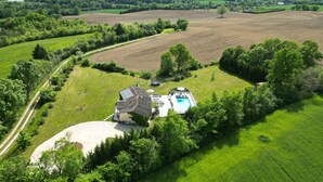 An aerial view of a property with a swimming pool, solar panels, and a large house surrounded by lush greenery and fields. - Maison les comtes - with swimming pool in Périgord (Sainte-Radegonde)