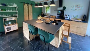 A modern kitchen with a central island, green walls, and a wooden bar counter. - Maison les comtes - with swimming pool in Périgord (Sainte-Radegonde)