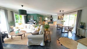 A spacious living area with a sofa, coffee table, and dining table. There is a piano in the background, and the room has large windows. - Maison les comtes - with swimming pool in Périgord (Sainte-Radegonde)