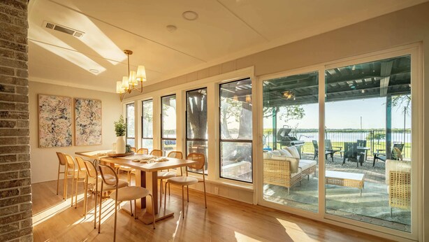 A spacious dining area with a large table and chairs, large windows, and a view of the outdoor patio.