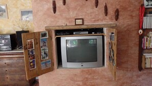 Un televisor fijado a la pared con un mueble de madera debajo, que contiene varios objetos.
