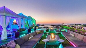 An outdoor lounge area with seating and a fire pit, overlooking a body of water.