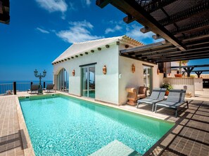 A poolside area with a clear view of the ocean, a small building with a tiled roof, and outdoor seating. - Villa Toscana Indoor Heated Pool, Sea view (Costa Adeje)