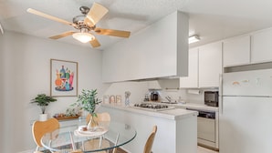 A modern kitchen with white cabinets, a glass island, and a ceiling fan. - 2 Mi to Downtown: Gated Condo in Palm Springs (Palm Springs)