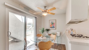 A modern kitchen with a gas stove, a ceiling fan, and a dining area with a glass table and wooden chairs. - 2 Mi to Downtown: Gated Condo in Palm Springs (Palm Springs)