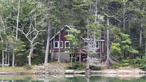 Una cabaña junto a un lago rodeado de árboles.