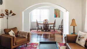 Una sala de estar con un sofá marrón, una mesa de centro y un comedor con una mesa y sillas de madera.