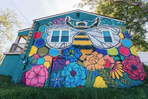 Un bâtiment orné d’une fresque colorée représentant de grandes fleurs et un motif d’abeille.