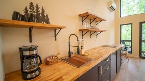 A modern kitchen with wooden countertops, a coffee maker, and shelves with glassware. - 2 Cabins, Hot Tub, 3 mi to BNR (Jasper)