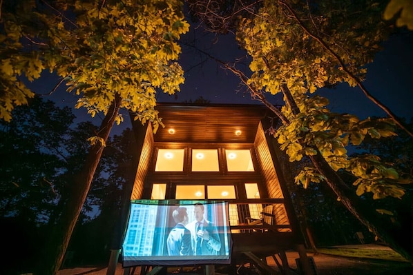 A modern building with a large screen displaying a scene.