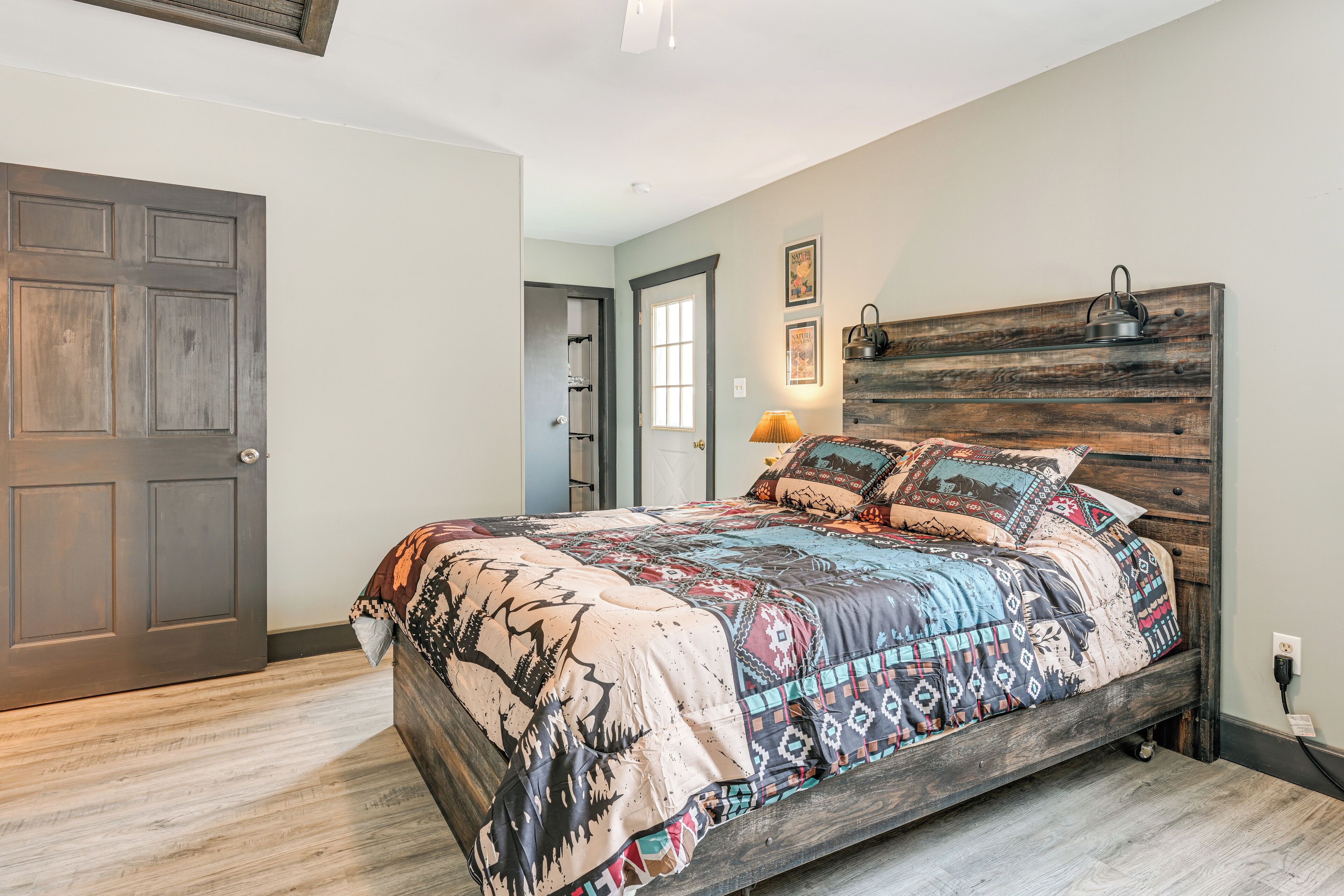 Un dormitorio con cama, cabecera de madera, una puerta y un ventanal.