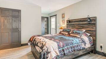 Un dormitorio con cama, cabecera de madera, una puerta y un ventanal.