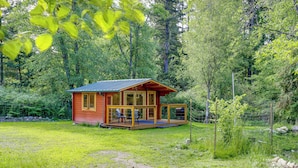 A wooden cabin with a porch, surrounded by a forest. - On Hobby Farm: Whidbey Island Tiny Home (Clinton)