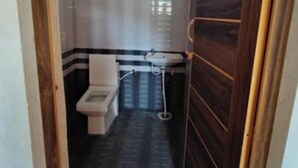 Une petite salle de bain étroite, avec des toilettes, un lavabo et une fenêtre.