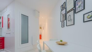 A modern kitchen with white cabinets, a red countertop, and a large window. - Suite Miro Eixample Barcelona (Barcelona)