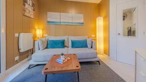 A modern room with a sofa, a coffee table, a painting, and a mirror. - Suite Miro Eixample Barcelona (Barcelona)