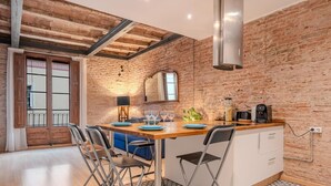 Una cocina con pared de ladrillo, vigas de madera en el techo y una isla central con taburetes de bar.