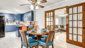 Une cuisine moderne avec des meubles bleus, un four à micro-ondes et un coin repas comprenant des chaises bleues et une table ronde.