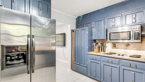 Une cuisine équipée d’appareils électroménagers en acier inoxydable, de meubles bleus et d’un plan de travail en granit.