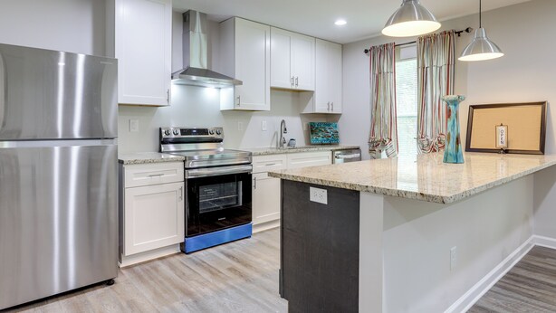 Una cocina moderna con electrodomésticos de acero inoxidable, armarios blancos y una isla central.