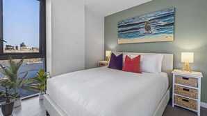 A bedroom with a large bed, a city view, a painting, and bedside tables with lamps. - Docklands Waterfront Elegance with Cityscape Views (Docklands)