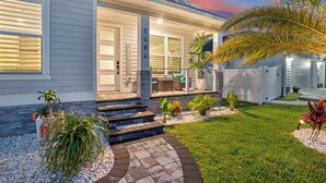 A modern house with a number '5484' on the door, a covered porch, and a well-maintained garden.