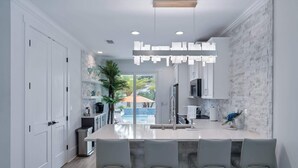 A modern kitchen with a large island, white cabinetry, and a view of a pool.