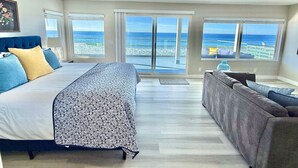 Un dormitorio con una cama grande, un sofá y vista al océano.