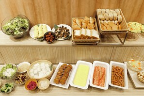Una mesa de buffet con diversos alimentos, como ensaladas, pan y carnes.