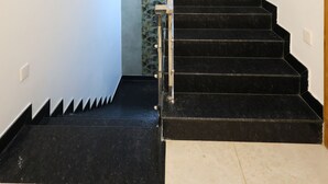 A staircase with black steps leading to a landing with a glass wall. - Star Eden Residency (Chinna Veerampattinam)