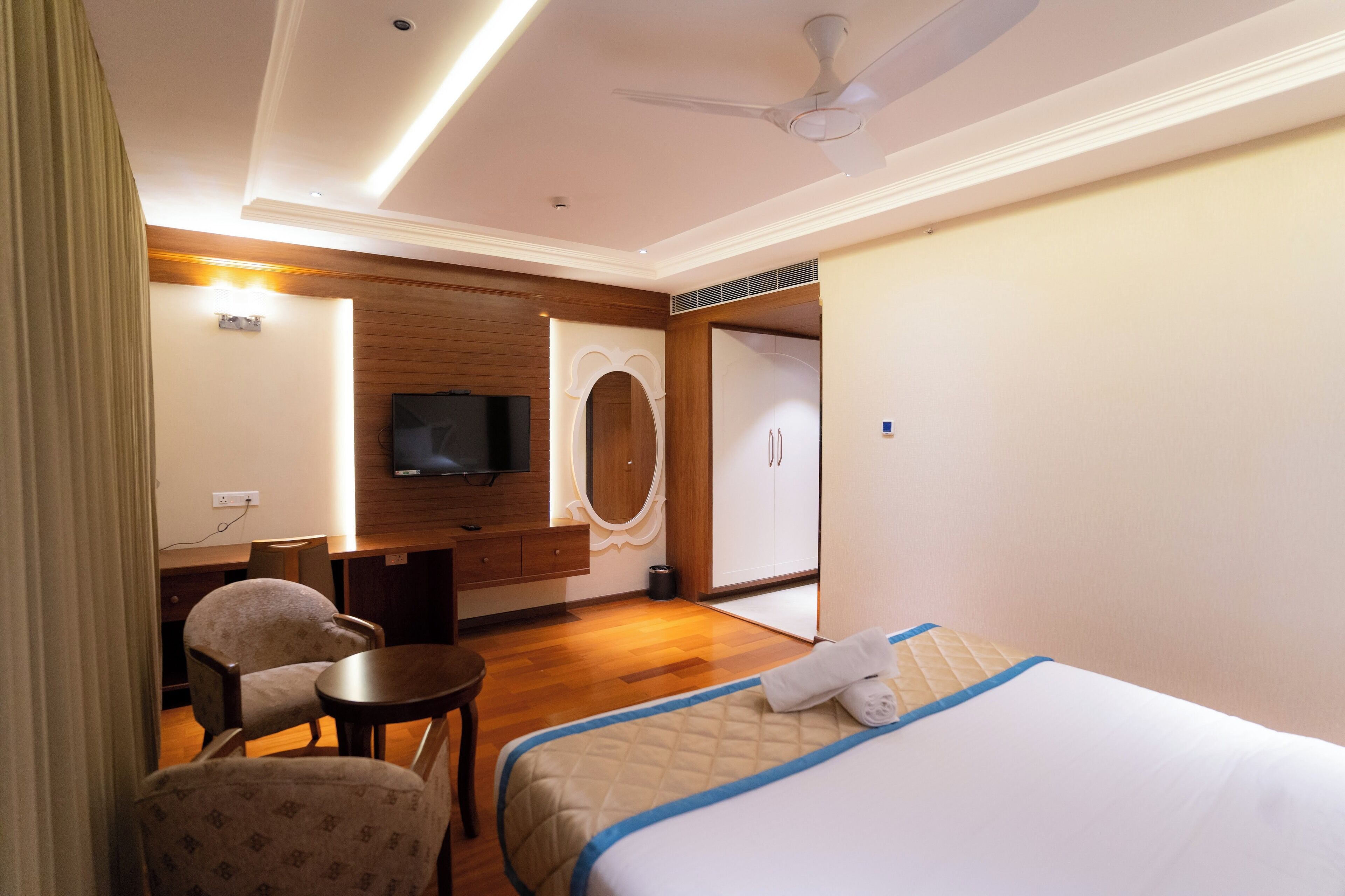 A hotel room with a bed, a desk, a chair, a television, and a wardrobe.