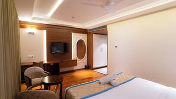 A hotel room with a bed, a desk, a chair, a television, and a wardrobe.