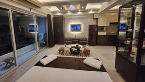 Una habitación de hotel moderna con cama, zona de estar, televisor y cocina.