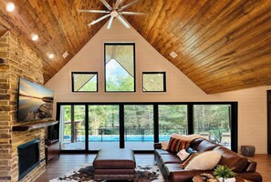 A modern living room with a fireplace, a large leather sofa, and a view of a swimming pool.